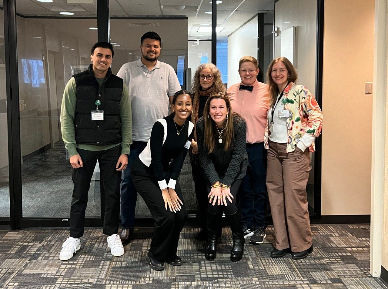 A group of people sit around a table and one person is standing and appears to be presenting