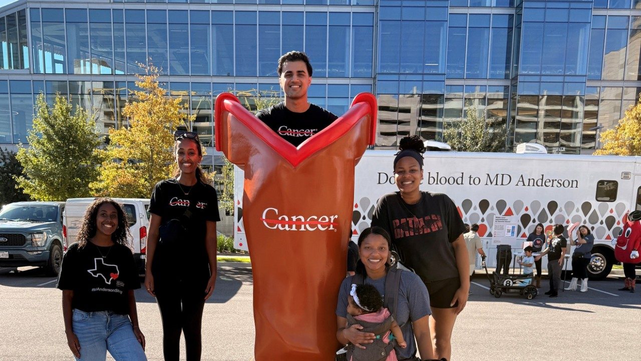 Five adults and a kid pose around the giant branded boot at the UT MD Anderson 2025 Boot Walk