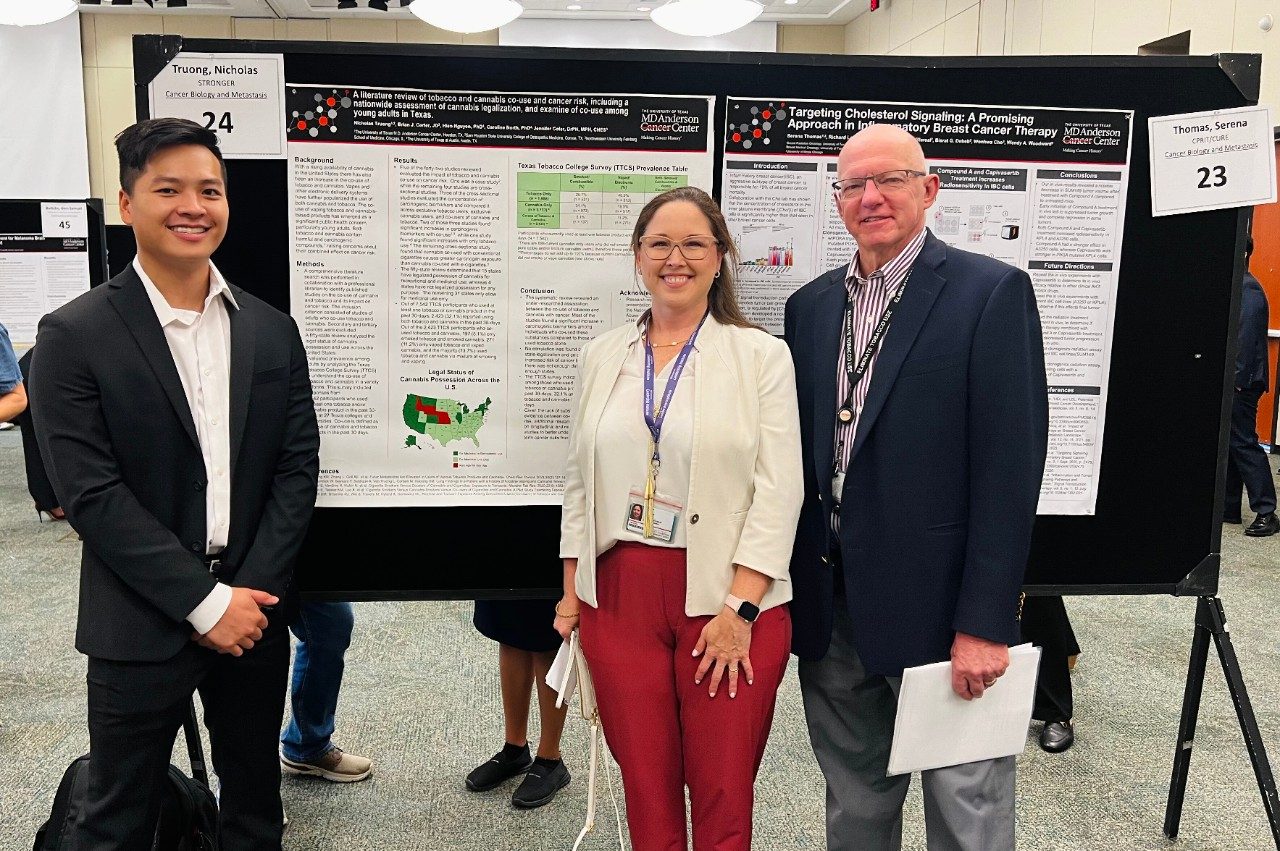 Three people posed in front of a scientific poster