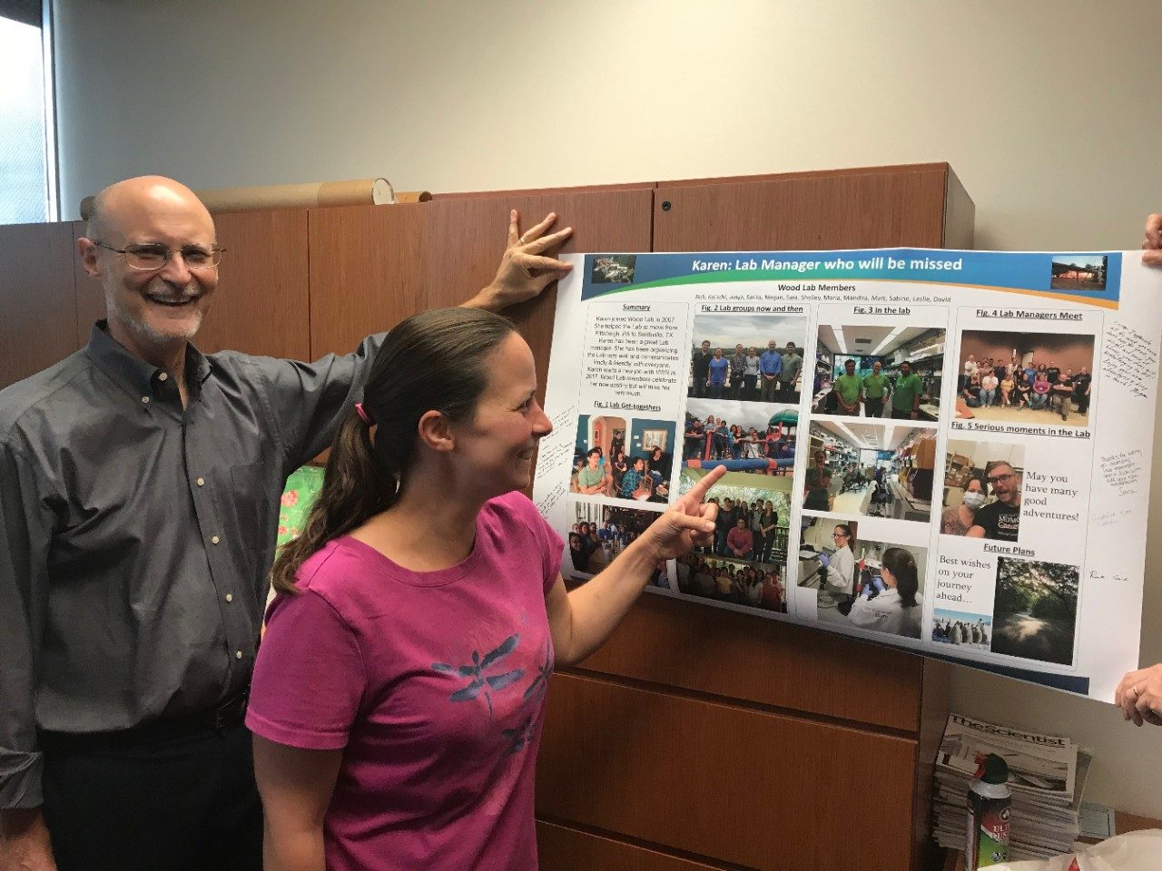 Dr. Wood and Karen Boulware, stand next to a mock scientific poster displaying photos taken from Karen's Life in the Lab