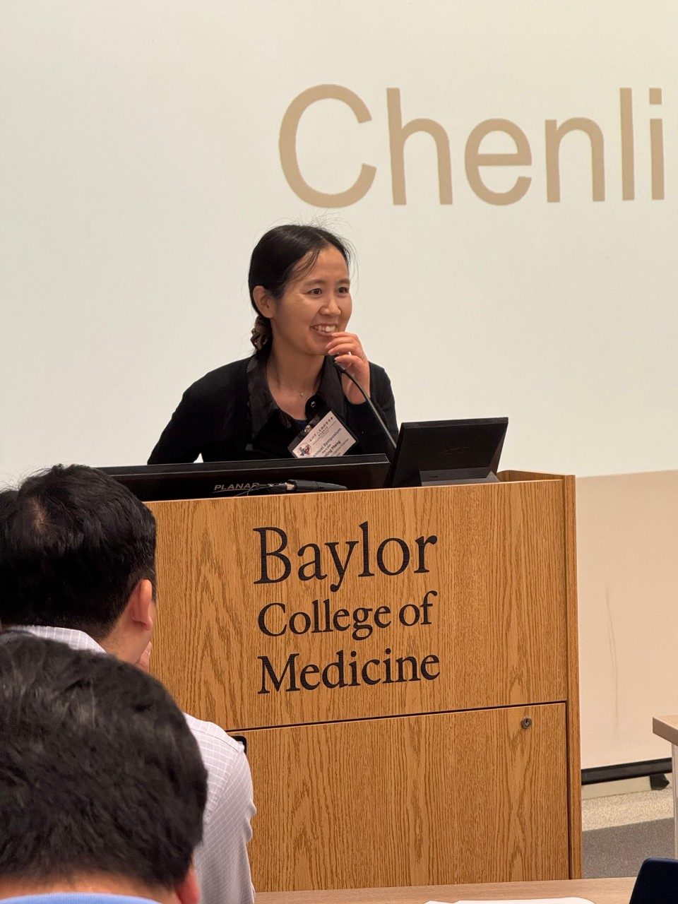 Woman standing at podium with Baylor College of Medicine logo