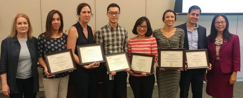 Eight people, some holding certificates, pose