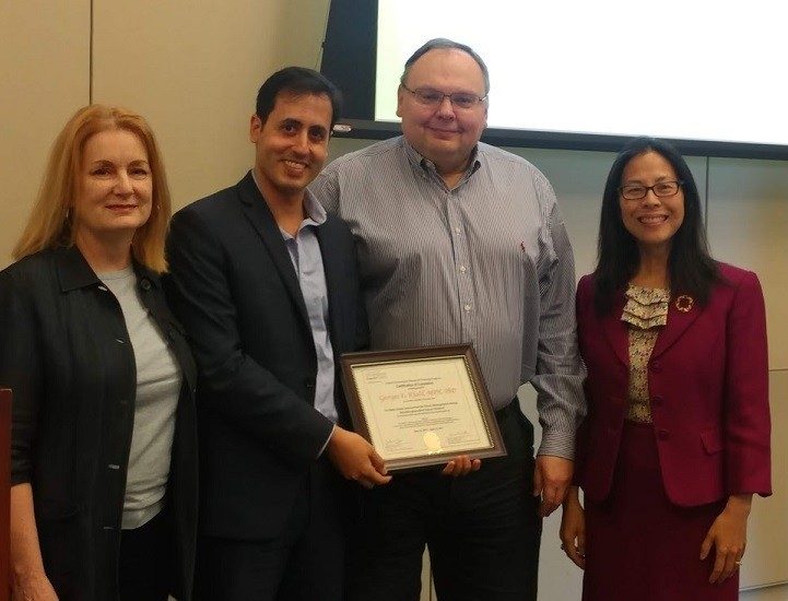 Four people stand with a certificate