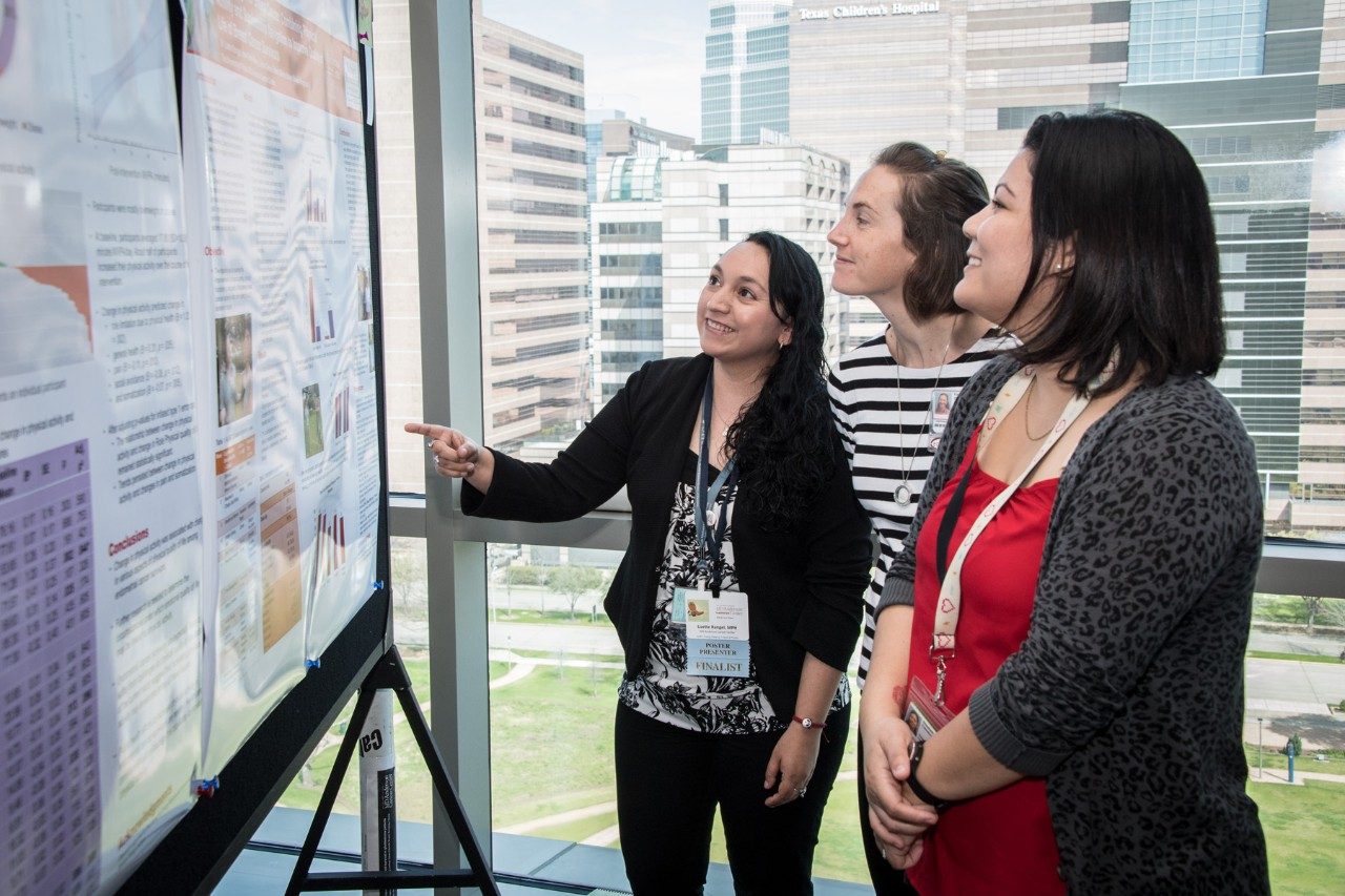 Three people look at a poster