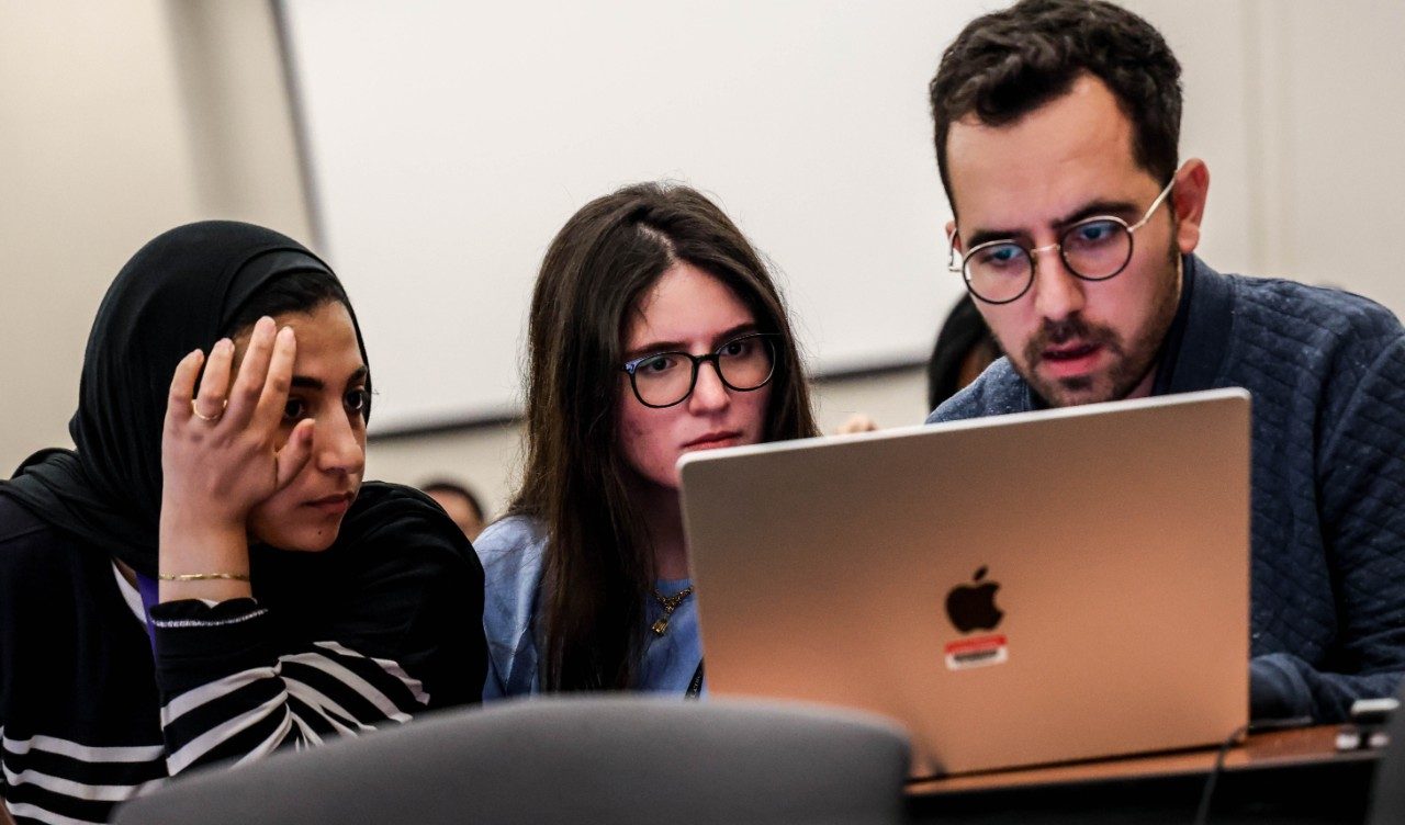 Three people looking at a laptop