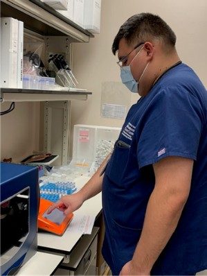 ITB lab member works at a piece of orange lab equipment