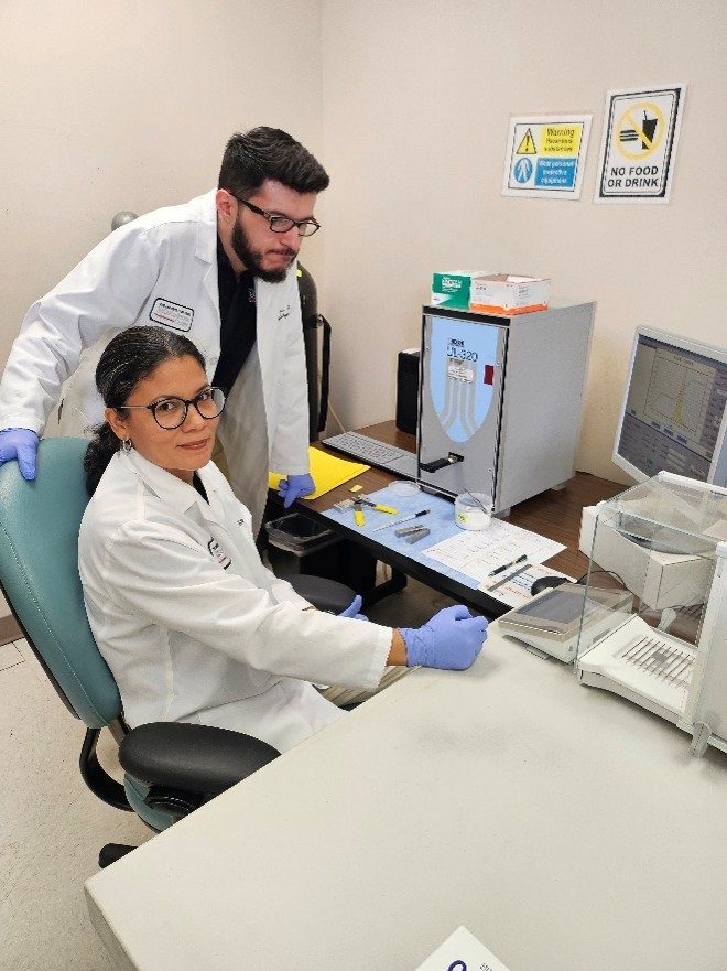 Two people in white coats at a desk with instruments